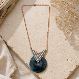 Geometric pendant necklace with turquoise and copper beadwork framing a deep blue circular stone pendant.