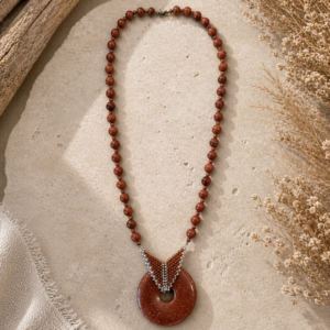 Warm brown beaded necklace with geometric beadwoven detail and glittering circular stone pendant centerpiece.