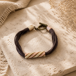 Multi-strand brown cord bracelet with soft pink and gold beadwoven accents and bronze toggle clasp.