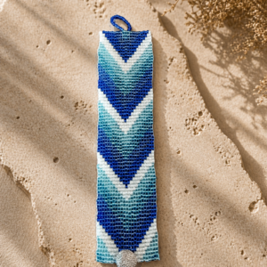 Loom-woven bracelet in layered blue, aqua, and white chevron pattern with silver button clasp.