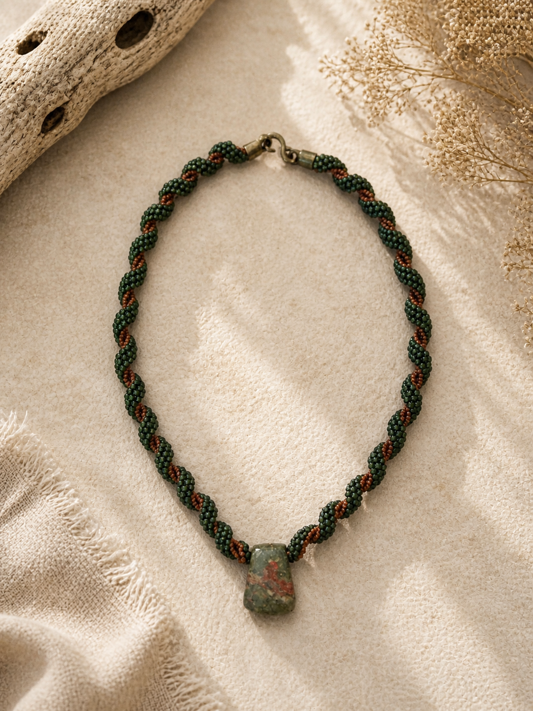 Twisted beadwoven rope necklace in deep green and copper with polished jasper stone pendant centerpiece.