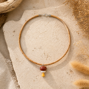 Minimal cork cord necklace with red and cream bead accents and small yellow geometric pendant detail.