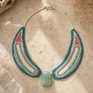 Statement necklace with turquoise, coral, and ivory bead embroidery surrounding a pale green stone centerpiece.