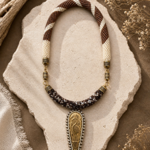Beadwoven rope necklace in cream and brown with brass accents and an Egyptian-inspired pendant centerpiece.