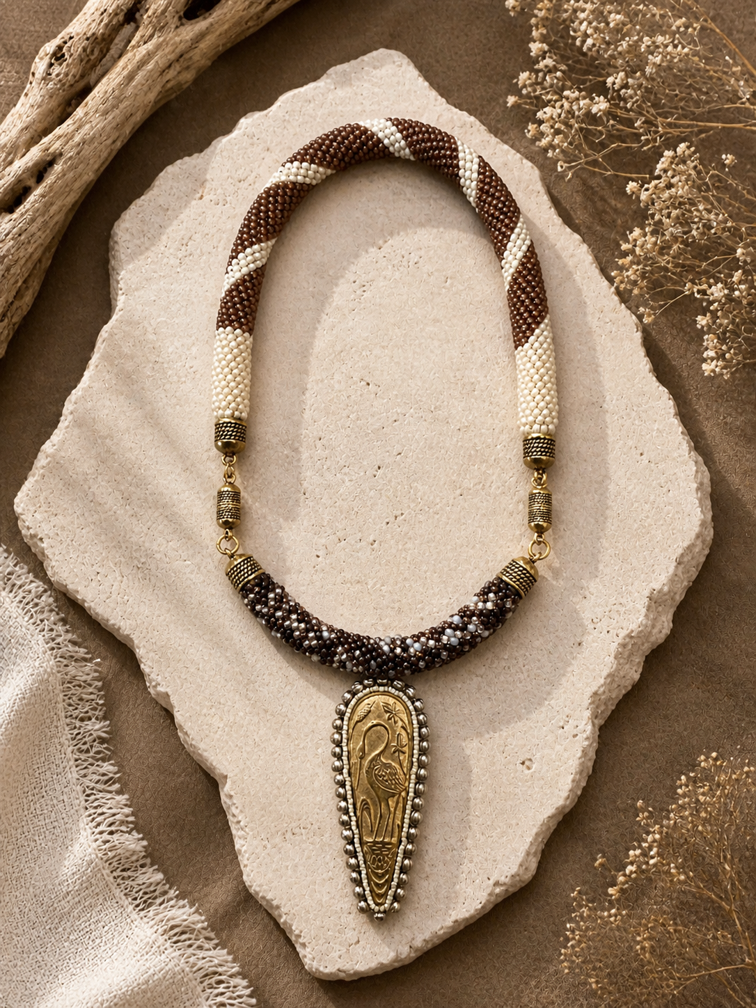 Beadwoven rope necklace in cream and brown with brass accents and an Egyptian-inspired pendant centerpiece.