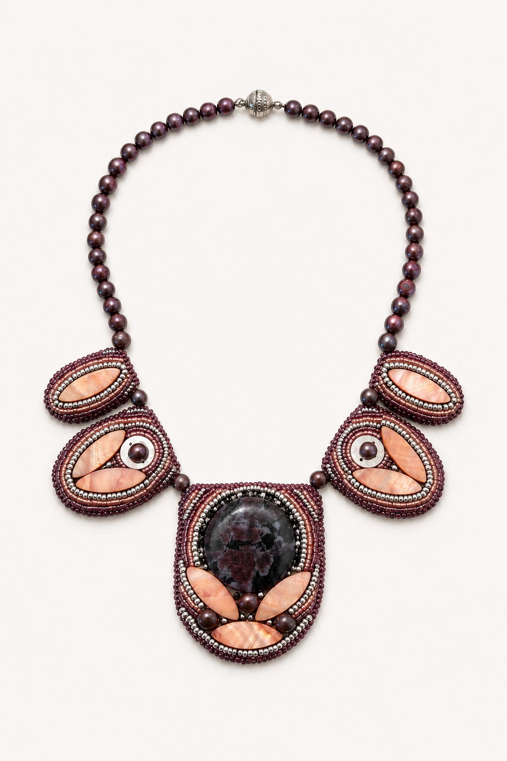 Statement necklace featuring plum pearl beads, blush shell accents, and intricate bead embroidery surrounding a dramatic floral-patterned cabochon centerpiece.
