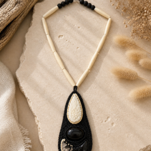 Bold black and ivory statement necklace with carved focal details, bead embroidery, and elongated bone-style beads.