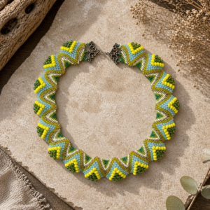 Geometric beaded collar necklace in lime green, blue, olive, and cream tones with a sculptural zigzag design.