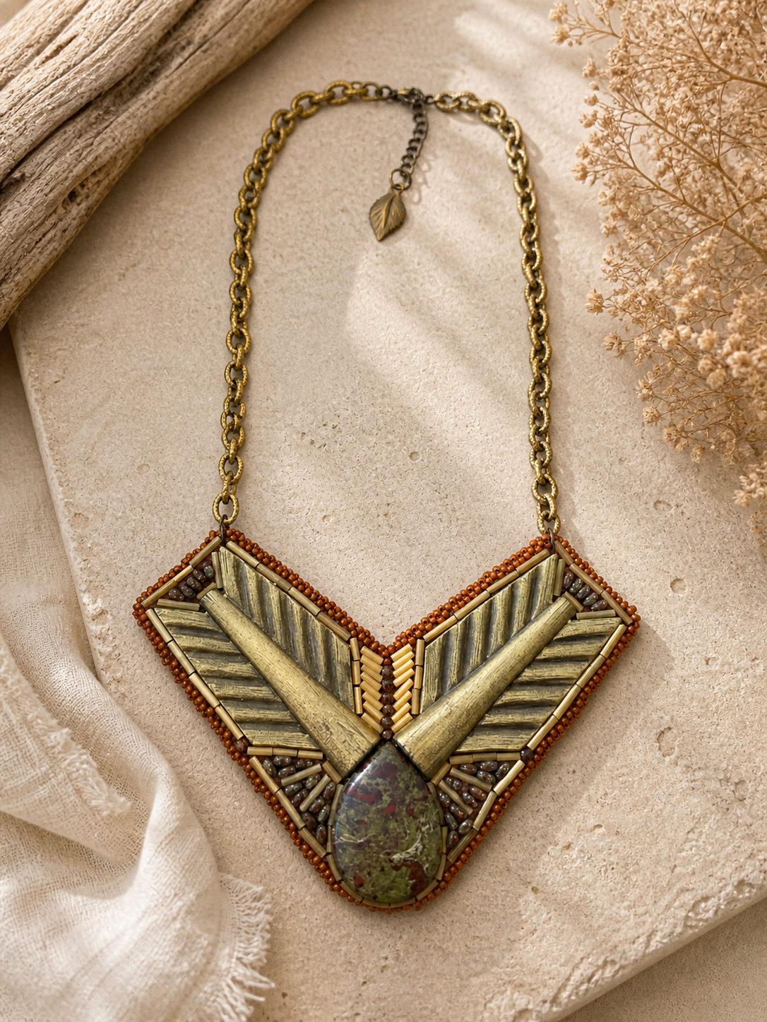 Geometric bead embroidered necklace with dragon blood stone focal, brass chain, and earthy bronze beadwork.