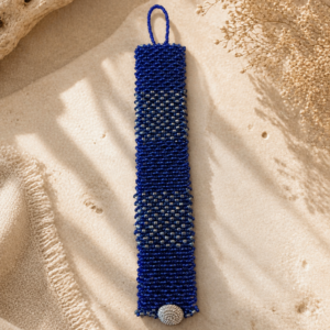 Handwoven cobalt blue bead bracelet with metallic accent bands and textured button closure.