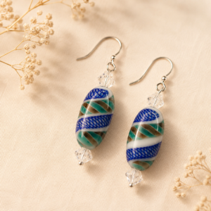 Handcrafted drop earrings with oval lampwork glass beads featuring cobalt blue, seafoam green, white, and tan swirls, accented by clear faceted crystals and sterling silver ear wires.