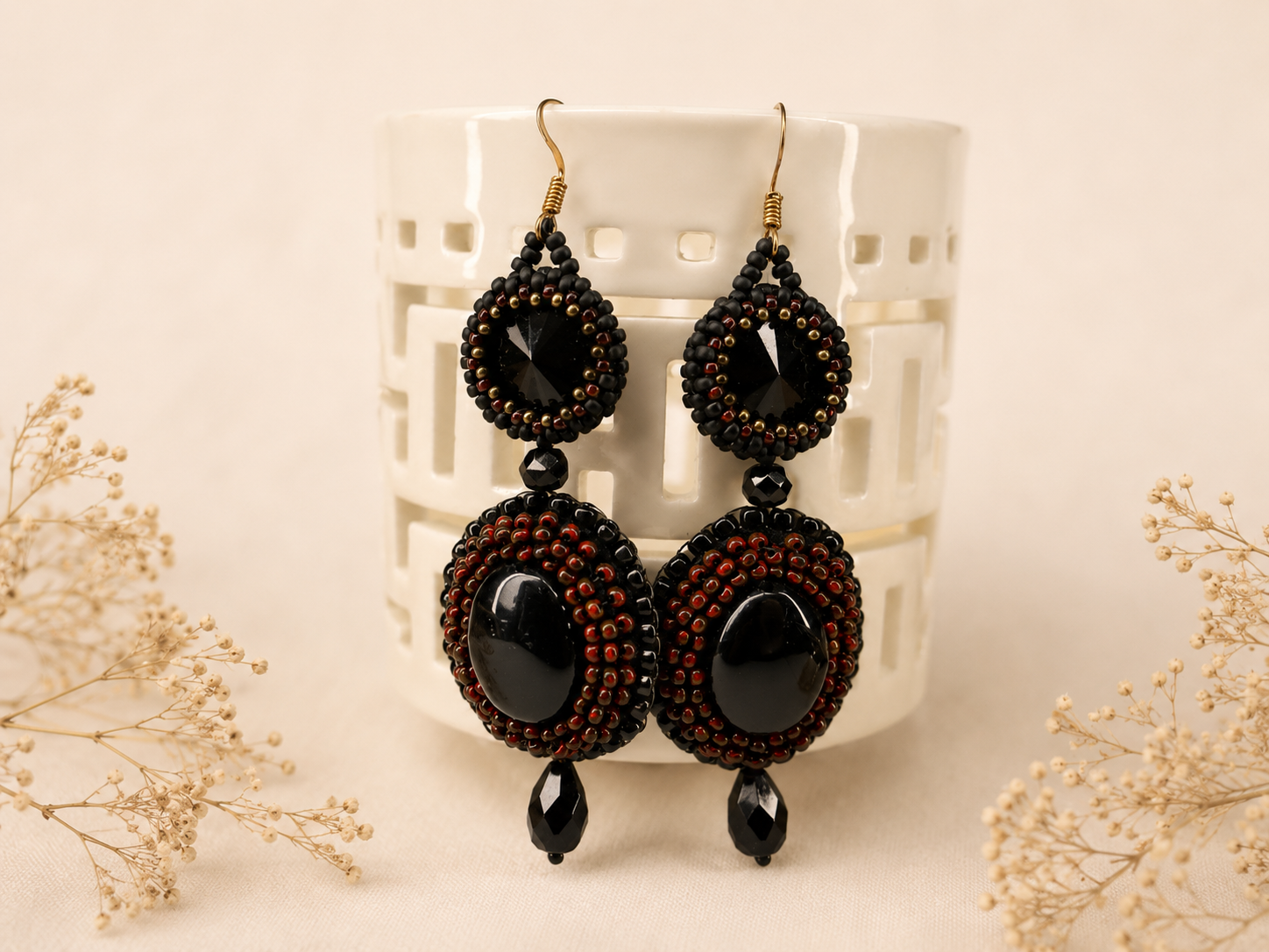 Handcrafted bead embroidered earrings featuring black oval cabochons, black faceted crystals, and intricate black and copper-red seed bead embroidery.