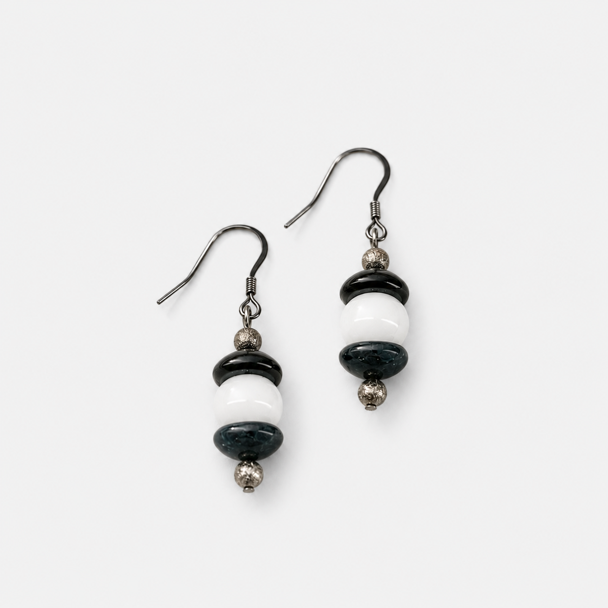Handcrafted drop earrings featuring navy blue lampwork glass beads, white glass beads, sterling silver accent beads, and silver ear wires.
