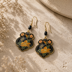Floral enamel dangle earrings featuring black, gold, blue, green, and coral details suspended from faceted black crystal beads and gold-tone ear wires.