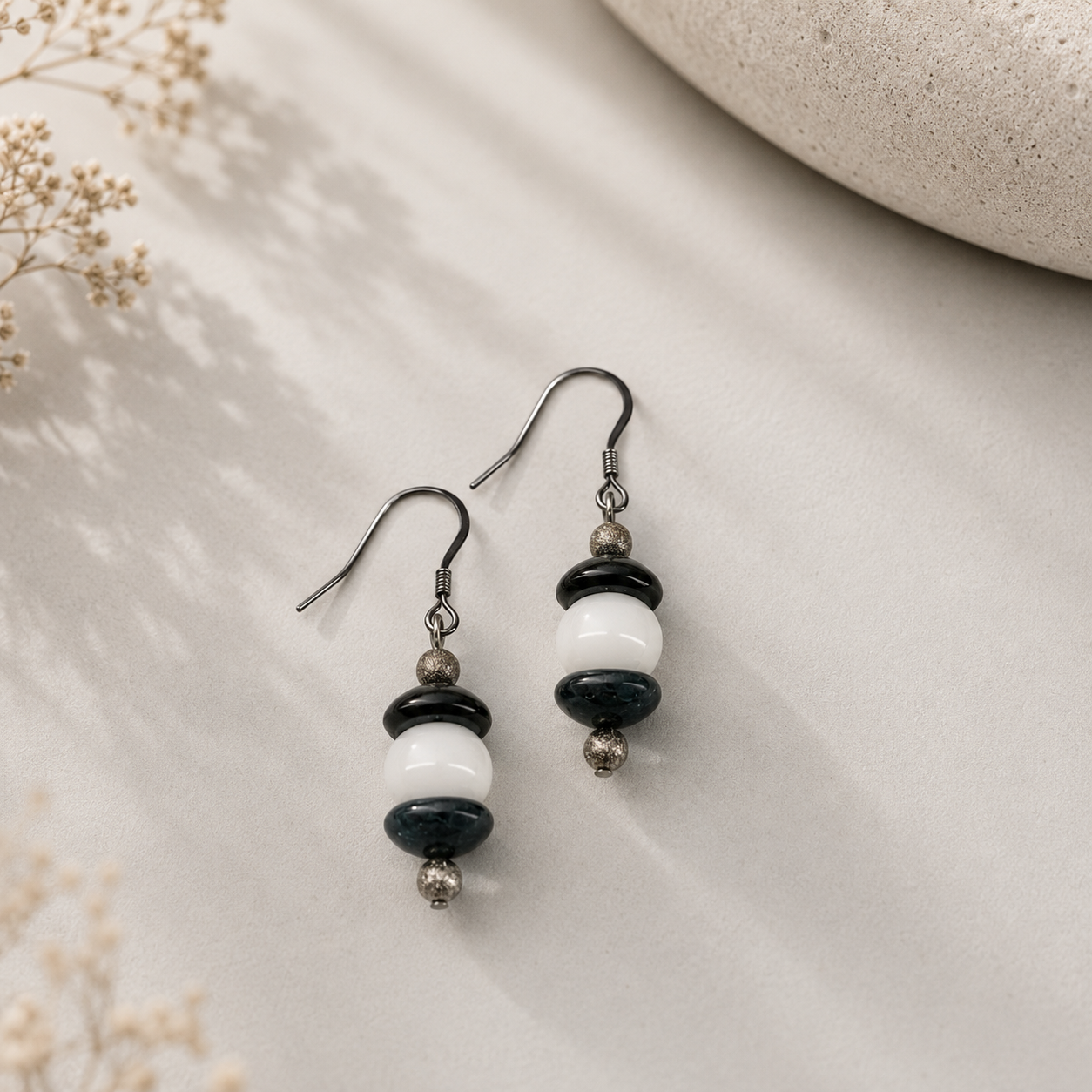 Handcrafted drop earrings featuring navy blue lampwork glass beads, white glass beads, sterling silver accent beads, and silver ear wires.