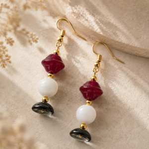 Geometric dangle earrings featuring cherry red glass beads, ivory white round beads, smoky blue glass discs, and gold-tone ear wires.