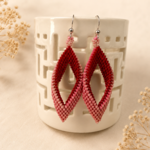 Handwoven geometric earrings featuring a twisted open diamond shape created from red and pink Miyuki seed beads with sterling silver ear wires.