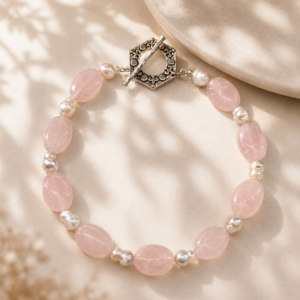 Handmade necklace featuring large blush rose quartz oval beads paired with freshwater pearls and finished with an ornate silver toggle clasp, displayed on a soft neutral background.