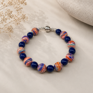 Handcrafted bracelet featuring multicolored artisan beads with swirling coral, blue, lavender, turquoise, and peach patterns, accented with cobalt blue glass beads and a silver magnetic clasp.